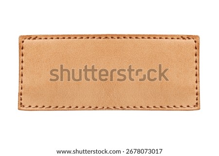 Brown leather label closeup. Rectangular patch isolated on white background. Jeans clothing leather detail. Fashion apparel blank leather badge for design. Closeup of stitched leather patch.