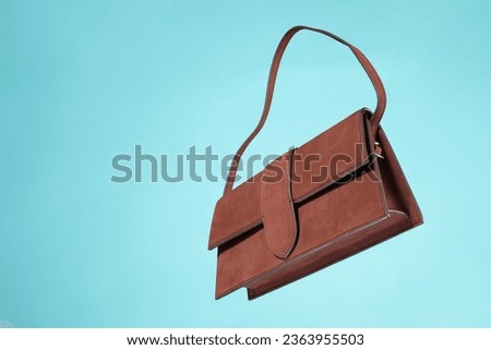 Brown leather ladies bag flying on blue background. Fashionable and modern womens handbag.