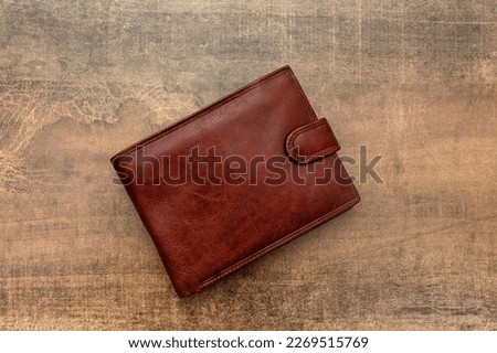 Brown leather men's wallet on a brown background. View from above.