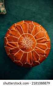 Brown Leather Moroccan Pouf With White Embroidery On Teal Carpet