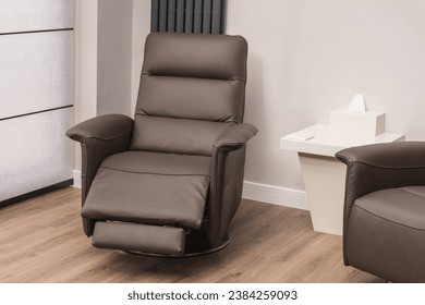 Brown leather recliner armchair in modern home. Solid surface coffee table and wood effect flooring.