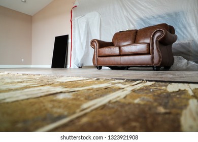 A Brown Leather Sofa In An Empty Room With Broken Floorboards