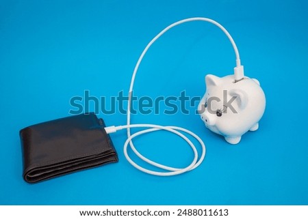 Brown leather wallet charging from a white porcelain piggy bank,   on blue background, online banking metaphor