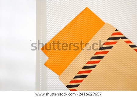 
Brown letter envelope has a rectangular shape with colorful lines on the side which is usually called airmail. The envelope is exposed to the shadow of the steel wire.