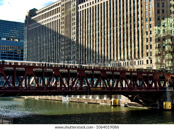 Brown line el train\
crosses elevated track over the Chicago River alongside the\
Merchandise Mart.