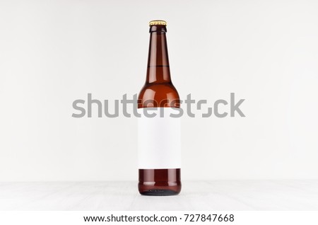 Brown longneck beer bottle 500ml with blank white label on white wooden board, mock up. Template for advertising, design, branding identity.