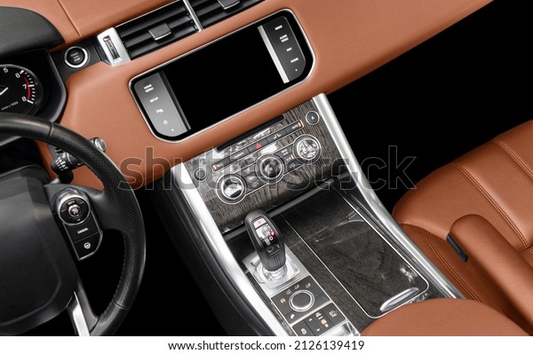 Brown luxury modern car Interior. Steering wheel,\
shift lever and dashboard. Detail of modern car interior. Automatic\
gear stick. Part of leather seats with stitching in expensive\
car