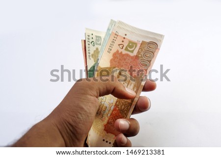 Brown man holding multiple pakistani currency notes on white background