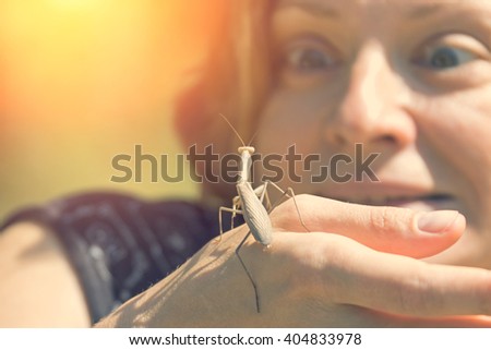 Brown mantis crawling on his hand frightened young woman