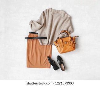 Brown Midi Pencil Skirt, Beige Knitted Oversize Sweater, Bag, Belt, Black Loafers Or Flat Shoes On Grey Background. Overhead View Of Women's Casual Day Outfit. Flat Lay, Top View. Women Clothes.