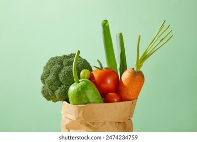 A brown paper bag contains many types of fresh vegetables, isolated on green background. Photo for product advertising, which has organic ingredient, blank space for designing - Powered by Shutterstock