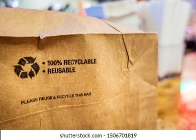 Brown paper bag that is 100% recyclable and reusable on a counter. A printed plea for user to recycle and reuse this bag as a form of packaging.