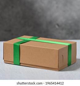 Brown Paper Board Box With Green Satin Ribbon, Shoot On White Wooden Top With Dark Texture Background.