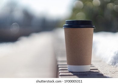 brown paper cup with black plastic lid on the street with blurred background