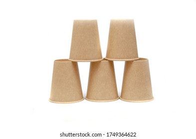 Brown Paper Cup For Coffee, Tea, A Drink From Environmental Materials On A White Background. The Male Hand Builds A Pyramid Of Cups In Macro And Overall Plan. Place For Text On The Left And Right.