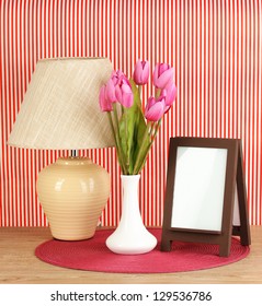 Brown Photo Frame And Lamp On Wooden Table On Red Striped Wall Background