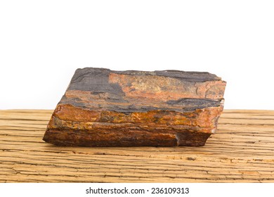 Brown piece of petrified wood on old oak surface, white background. Ancient natural gem stone.
