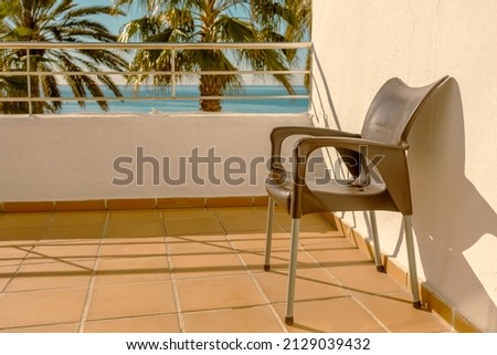 brown plastic chair on the apartment terrace and palm tree background in sunny day, Spain