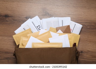 Brown postman bag with newspapers and mails on wooden table, flat lay - Shutterstock ID 2105395142