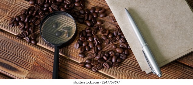 Brown roasted coffee beans, magnifying glass, pen and notepad on pine plank table. Research, checking and examination of coffee quality. Analysis of the content of nutrients in coffee. Close-up - Shutterstock ID 2247757697