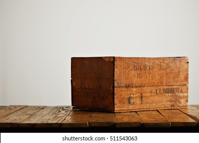 Brown rustic wooden wine box with barely legible black letters on a wooden table against white wall background - Powered by Shutterstock