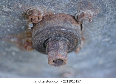 Brown Rusty Iron Bolts And Nuts With An Axle On A Gray Metal Panel