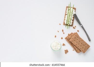 Brown Rye Crispy Bread (Swedish Crackers) With Spread Cottage Cheese, Decorated With Thin Green Onion, On White Background With Space For Text, Top View. Healthy Snack Concept