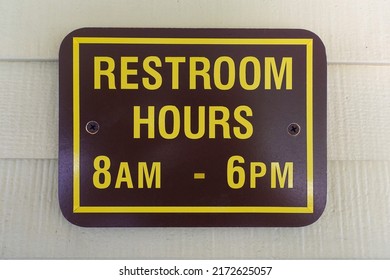 A Brown sign indicating restroom hours of operation.