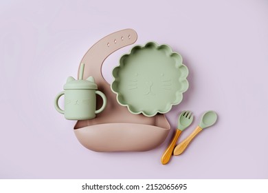 Brown silicone baby bib and with plate and drinking cup. Serving baby. First baby accessories for dinner. Top view, flat lay
