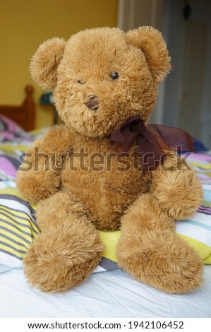 Brown soft teddybear sitting on a bed