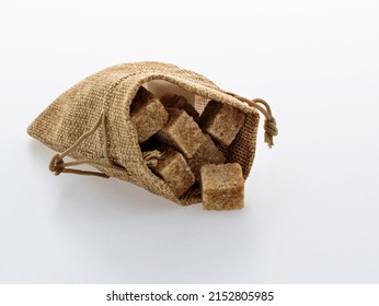 Brown Sugar Cubes In Sack Bag On White Background.