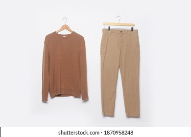 Brown Sweater And Khaki Pants Hanging On Wooden Clothes Hanger