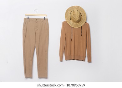 Brown Sweater And Khaki Pants Hanging On Wooden Clothes Hanger