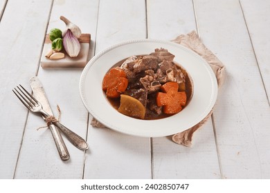 A brown tablecloth was spread on a white wooden table, and steamed pork ribs with flower-shaped carrots were placed on a ceramic plate and served with kimchi using wooden chopsticks. - Powered by Shutterstock