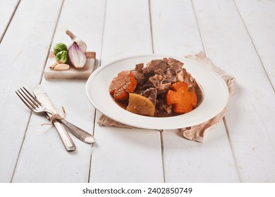 A brown tablecloth was spread on a white wooden table, and steamed pork ribs with flower-shaped carrots were placed on a ceramic plate and served with kimchi using wooden chopsticks. - Powered by Shutterstock