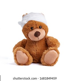 Brown Teddy Bear With A Bandaged Head In A White Medical Bandage On A White Background, Concept Of Child Trauma, Headache