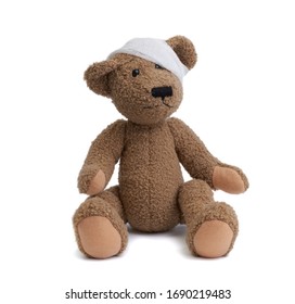 Brown Teddy Bear With A Bandaged Head In A White Medical Bandage On A White Background, Concept Of Child Trauma, Headache