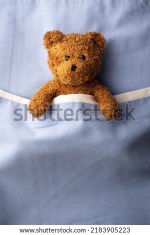 Brown teddy bear laying on blue bed. Pediatrical and child medicine concept