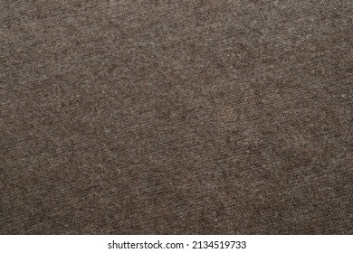 Brown textured background made of natural hand-knitted wool yarn. Warm cozy knitted clothes or handmade plaid. Wool shawl made of goat or sheep wool