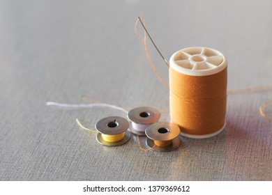 Brown Thread Spindle With Steel Thread Bobbin And Needles For Hand Sewing Close-up.