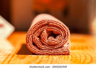 Brown three-ply microfibre tea towel rolled up on a wooden surface