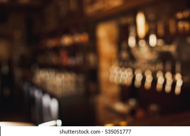Brown toned bar out of focus blurred background with beer cranes and menu on chalkboard