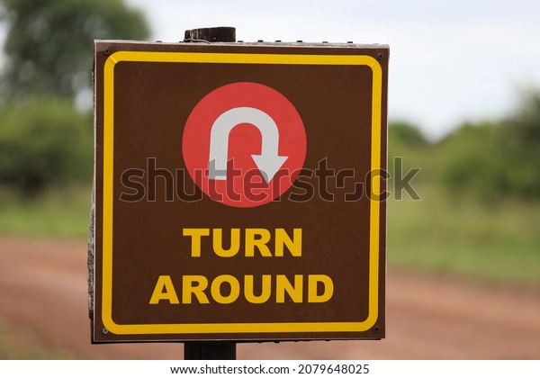 Brown Turn Around Road Sign\
with blurred background. Direction, mistake, road, travel, choice\
concept.