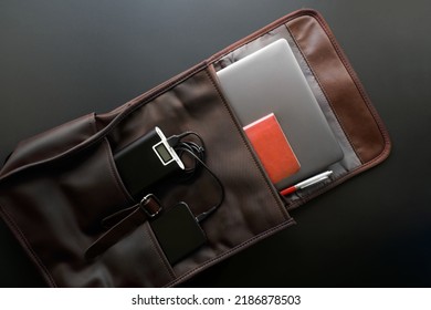 Brown Urban Backpack, Satchel Or Bag With Smartphone And Laptop, Power Bank, Notepad And Pen. Gadgets For Study And Travel. Dark Background. Copy Space. Close-up