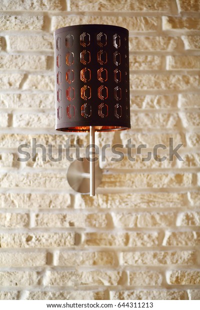 Brown wall bracket lamp are on white brick wall,\
close up view