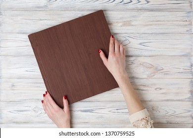 Brown Wedding Photo Book With  Leather Cover. 
Stylish Wedding Photo Album Close Up.
Person Opens A Square Photobook.
Family Photoalbum On The Table.
Womans Hand Holding A Family Photo Album