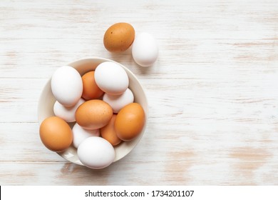 Brown and white eggs in bowl on wood background. Plate with brown and white chicken eggs on wooden table. Free-range organic eggs in bowl. Natural healthy food concept. Top view, flat lay, copy space. - Powered by Shutterstock