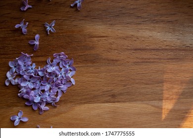 Brown wood background with heart of purple lilac flowers, empty template for text
