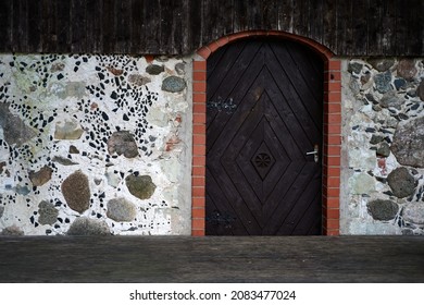 Brown wood door with red edging in stone wall 