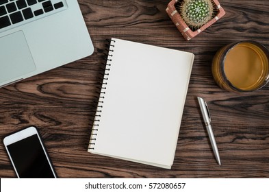 Brown Wood Office Desk Table With A Book, Pen, Cactus And Phone For Working In Top View And Copy Space.